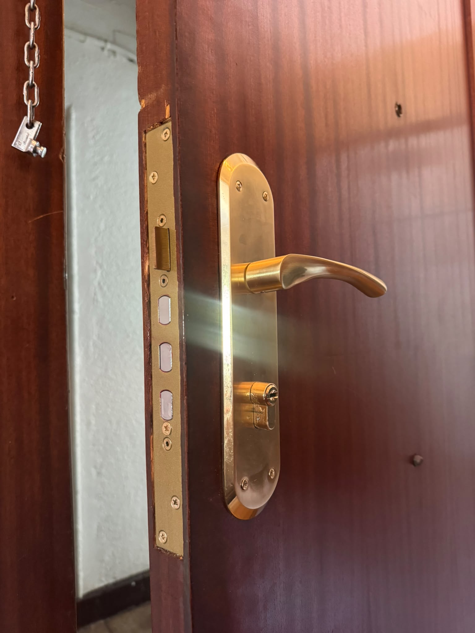 Cerradura con maneta dorada y bombín en puerta madera