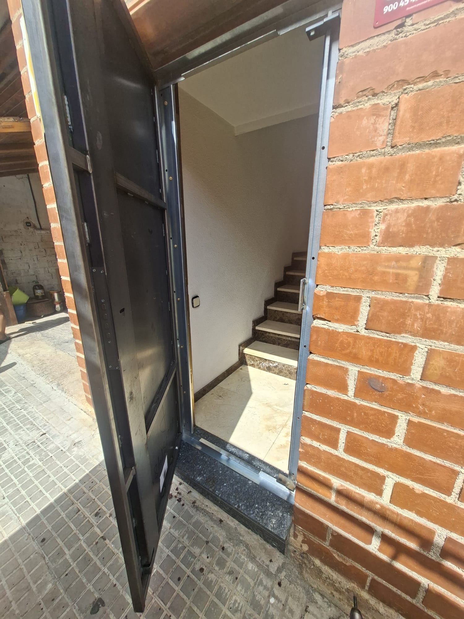 Cerco de acero anclado al muro durante la instalación de una puerta acorazada en un portal